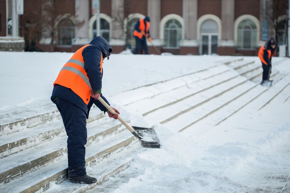 Workers scooping snow off of public pavements